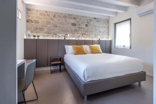 een slaapkamer met een bed en een bakstenen muur bij Portone180 Guest House in Roveredo in Piano
