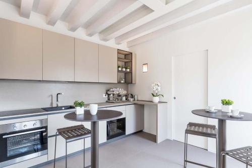 a kitchen with white cabinets and two tables and chairs at Portone180 Guest House in Roveredo in Piano