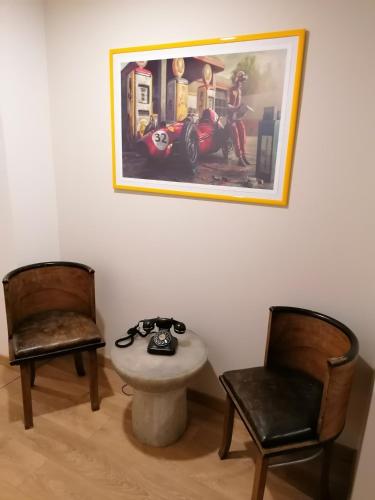 une chambre avec deux chaises, une table et une photo dans l'établissement Ferrari Formula 1, à Orio al Serio