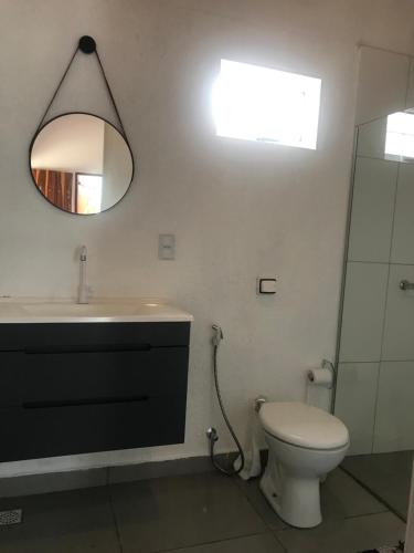 a bathroom with a toilet and a sink and a mirror at Chácara buriti in Pirenópolis