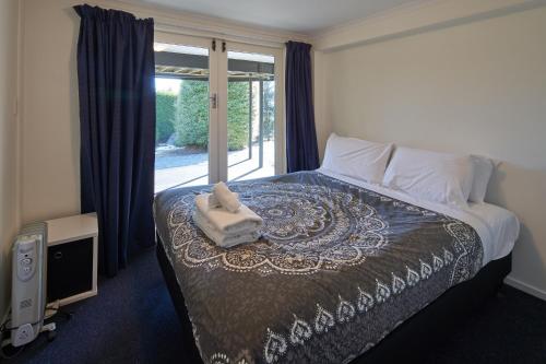 a bedroom with a bed and a large window at Serendipity - Lake Tekapo in Lake Tekapo