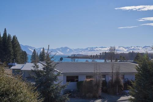 a house with snow covered mountains in the background at Serendipity - Lake Tekapo in Lake Tekapo