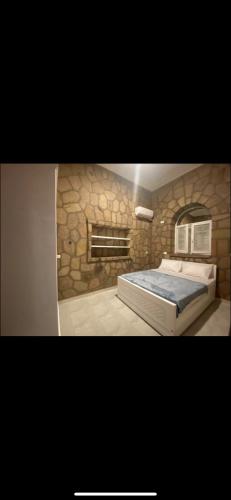 1 dormitorio con 1 cama grande y pared de piedra en Nile palace villa, en Luxor