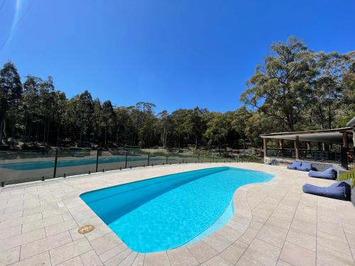 a swimming pool with blue water in a yard at Kianinny Bush Cottages in Tathra