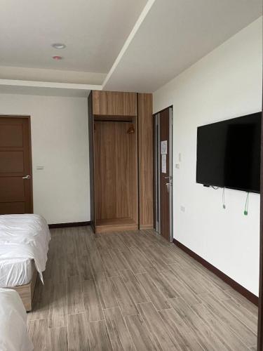a hotel room with a bed and a flat screen tv at Ferry Head Leisure Club in Yuanshan