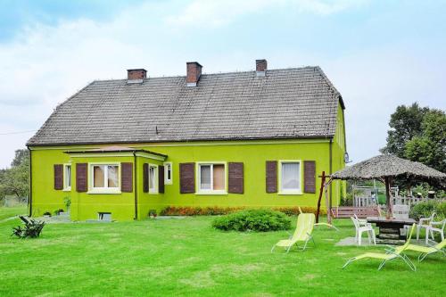 a yellow house with a yard with chairs and a gazebo at Comfortable 2 person holiday apartment in the countryside Drezno in Stare Wierzchowo