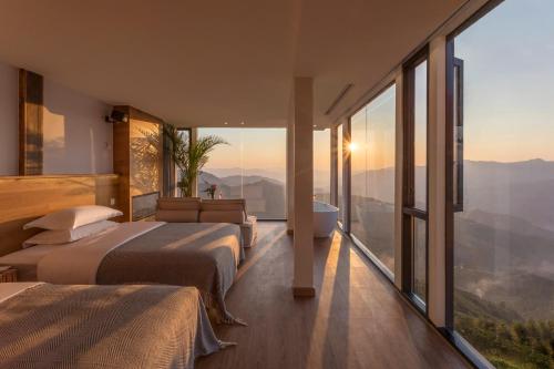 two beds in a room with large windows at Rice View Lodge in Longsheng