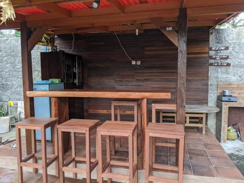 un bar en bois avec quatre tabourets et une table dans l'établissement Loka Loka Ubud, à Gianyar