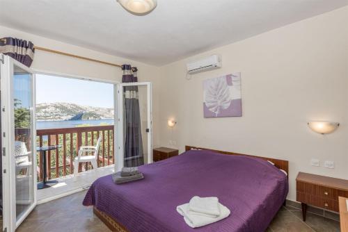 a bedroom with a purple bed and a balcony at Rooms Zdravko in Stara Novalja