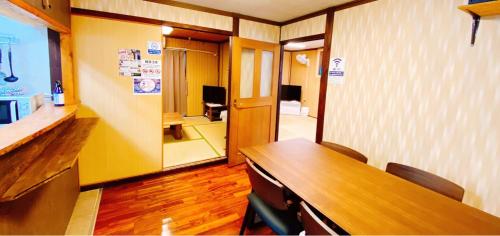 a conference room with a wooden table and a hallway at Okinawa Naha JinJin -沖縄伝統体験型宿じんじん- in Naha