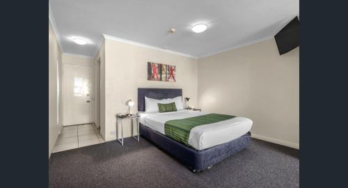 a bedroom with a bed with a green blanket at The Wellington Apartment Hotel in Brisbane