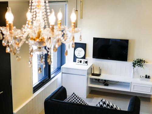 a living room with a chandelier and a tv at Tropicana 218 Macalister Studio with Seaview in George Town