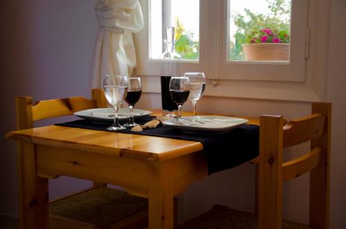 una mesa de madera con dos copas de vino. en Helen's Budget Accommodation, en Aliki