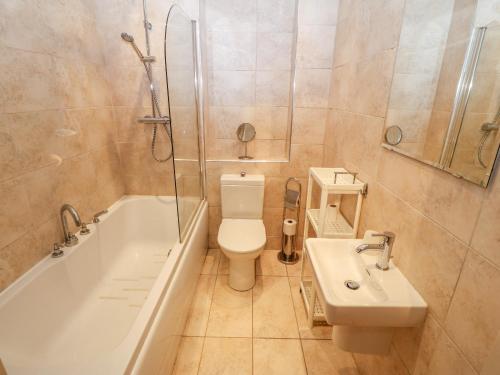 a bathroom with a toilet and a tub and a sink at Linksway in Morfa Nefyn