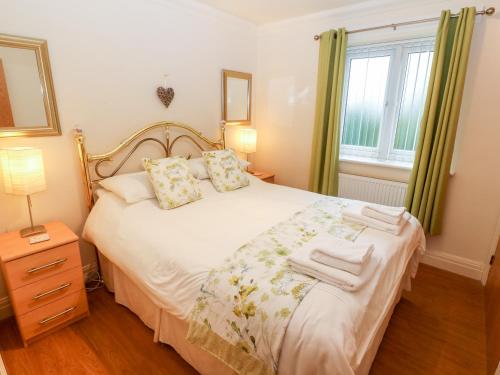 a bedroom with a bed and a window at Linksway in Morfa Nefyn