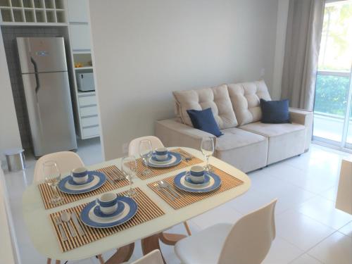 uma sala de estar com uma mesa e cadeiras e um sofá em Palm Village Acqua - Apartamento Premium - Em frente à piscina - Porto de Galinhas em Porto de Galinhas