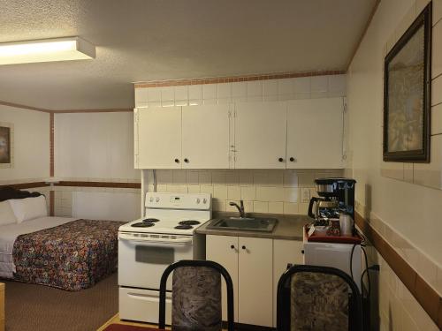 a small kitchen with a stove and a bed at Vista Motel in Vegreville
