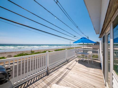 a balcony with a table and an umbrella and the beach at Sea Latch Inn in York Beach