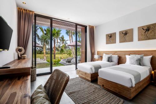 a bedroom with two beds and a desk and a window at Villa Florentine by BaliSuperHost in Ubud