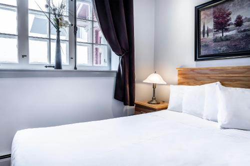 a bedroom with a white bed and a window at Hotel Louisbourg in Quebec City