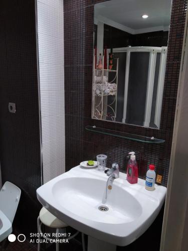 La salle de bains est pourvue d'un lavabo blanc et d'un miroir. dans l'établissement Loja centro., à Loja
