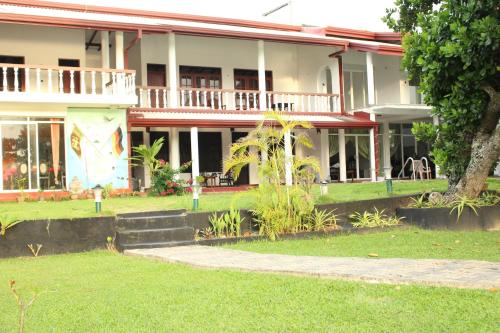 a building with a green lawn in front of it at Residence Jasmine in Aluthgama