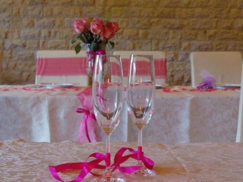two wine glasses on a table with a vase of roses at Ośrodek Pegaz in Duszniki Zdrój