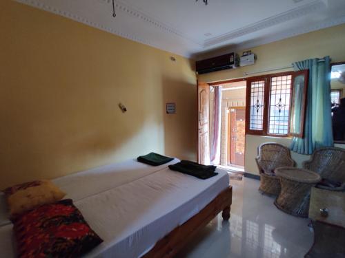 a bedroom with a bed with two chairs and a window at All Is Well in Hampi