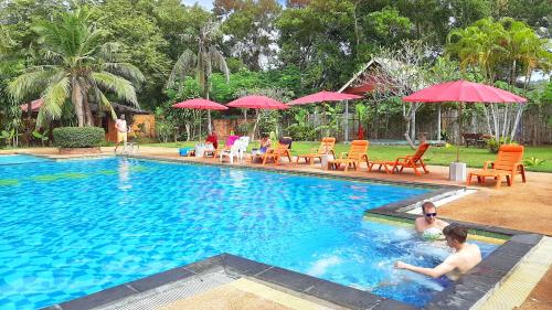 a group of people in a swimming pool with umbrellas at Doo Dee Boutique Resort by Swiss Chalet in Ao Nang Beach