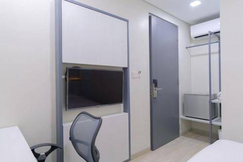 1 dormitorio con TV y silla en una habitación en LeGreen Suite Semanggi en Yakarta