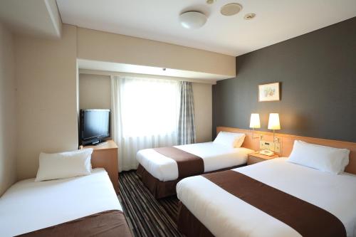 a hotel room with two beds and a television at Smile Hotel Tokushima in Tokushima