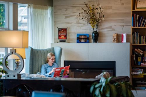 a woman sitting in a chair reading a book at River Inn at Seaside in Seaside
