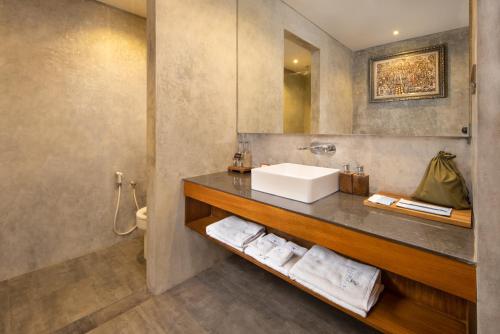 La salle de bains est pourvue d'un lavabo et d'un comptoir avec des serviettes. dans l'établissement Agrapana Beach Villa, à Gianyar