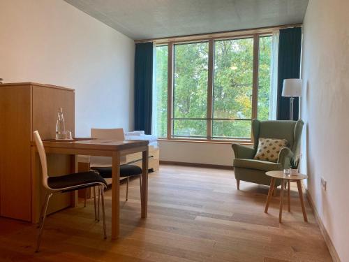 a living room with a table and chairs and a window at SUKHAVATI Apartments in Bad Saarow