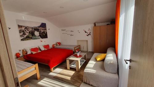 1 dormitorio con cama roja y sofá en Apartman Centar en Mostar