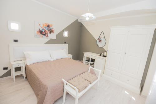 a white bedroom with a bed and a chair at B&B Le Scalette B&B San Marco in Abbadia San Salvatore