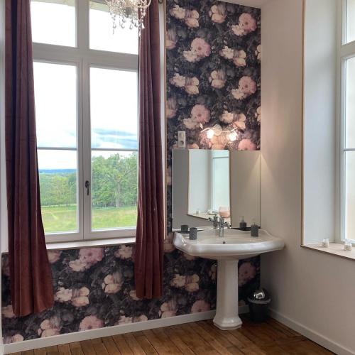 La salle de bains est pourvue d'un lavabo et d'un papier peint à fleurs. dans l'établissement Château de la Bouchatte chambre les Roses, à Chazemais