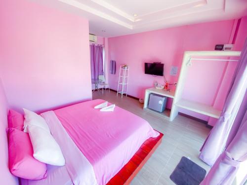 a pink bedroom with a bed and a television at BaanChomJan @ Suanphung in Suan Phung