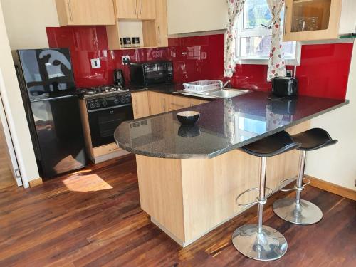 a kitchen with red walls and a counter with stools at Friendz Self Catering Guesthouse in Knysna