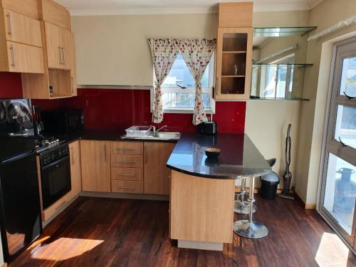 a kitchen with wooden cabinets and a black counter top at Friendz Self Catering Guesthouse in Knysna