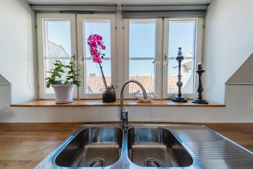 Österport - Visby Lägenhetshotell في فيسبي: مطبخ مع مغسلة وثلاث نوافذ