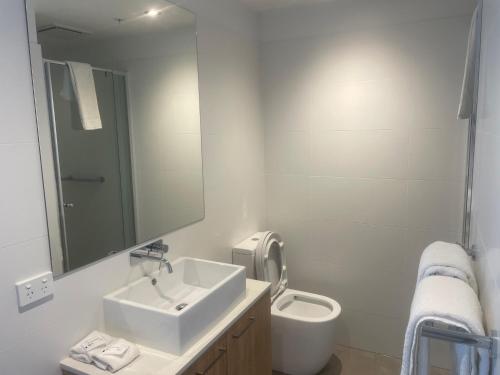ein weißes Bad mit einem Waschbecken und einem WC in der Unterkunft RNR on Franklin in Adelaide