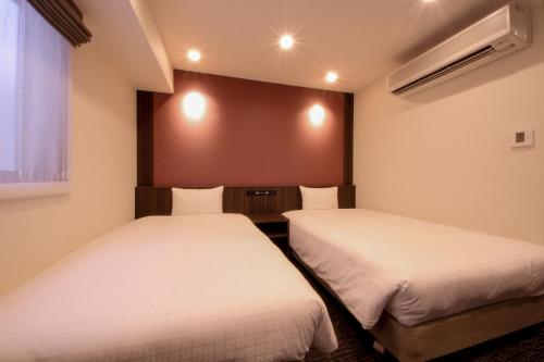 2 camas en una habitación pequeña con ventana en Compass Hotel Nagoya, en Nagoya