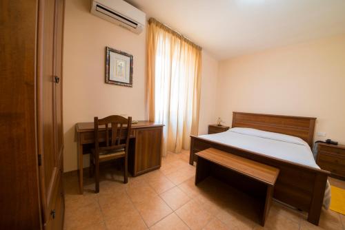 a bedroom with a bed and a desk and a chair at Hotel Fioriti in Matelica