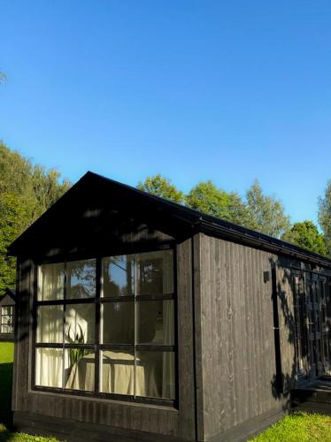a small building with a window in the grass at Ragnar Glamp Koknese in Koknese