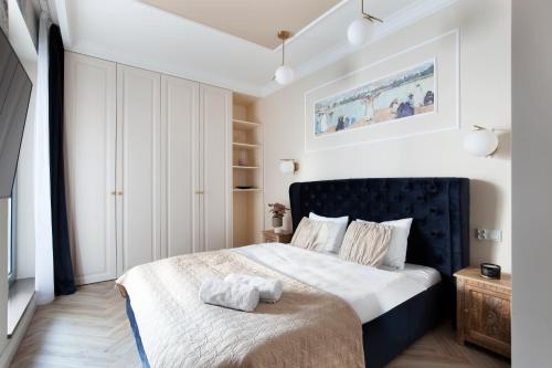 a bedroom with a bed with a blue headboard at Elite Apartments Granaria The View in Gdańsk