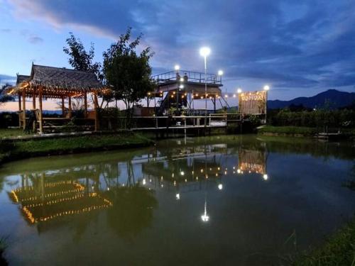 a pond with lights in the water at night at บวกบัววิวรีสอทร์ in Nan