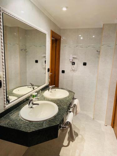 a bathroom with two sinks and a large mirror at Rey Sancho Palencia in Palencia