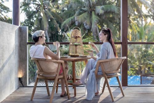 a man and woman sitting at a table on a porch at Agrapana Beach Villa in Gianyar