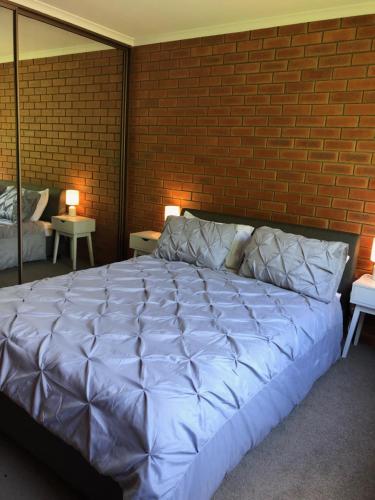 Cette chambre comprend un grand lit blanc et un mur en briques. dans l'établissement Kingston Pines, à Kingston 
